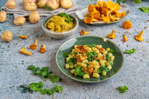 Pyszny obiad z ziemniaków: kluseczki z kurkami i zieloną pietruszką, obok miseczka curry i świeże kurki.