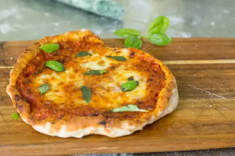 En perfekt pizza i airfryer, med smält ost och färsk basilika, serverad på en träskärbräda.