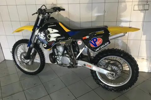 Husqvarna WR 250, gotowy do akcji. Czarne plastiki z żółtymi i niebieskimi akcentami, opony Metzeler.