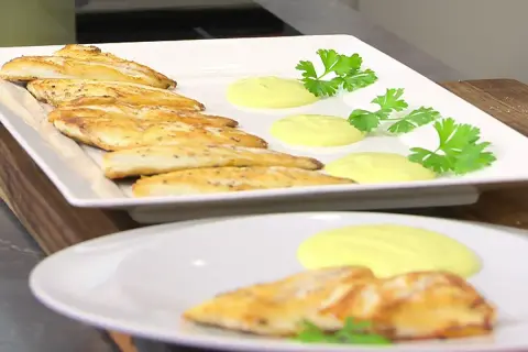 Pescado dorado a la plancha con salsa cremosa y perejil fresco. Un plato ligero y sabroso.