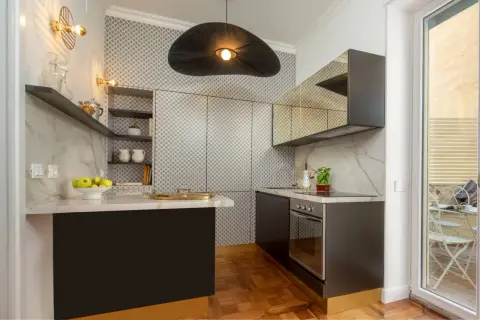 Cucine piccole ma eleganti, con piano in marmo, pensili a specchio e un'originale lampada a sospensione.