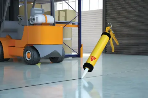 Pistola de Sikaflex lista para sellar juntas en un almacén, con una carretilla elevadora al fondo. Sikaflex para que sirve: sellar y unir.