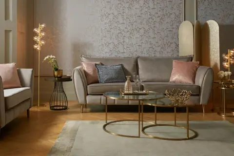 Przytulny salon glamour z szarą sofą, różowymi poduszkami i złotymi dodatkami.
