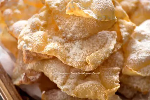 Chiacchiere croccanti, una deliziosa chiacchiere ricetta della nonna, cosparse di zucchero a velo.