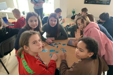 Dzieci układają litery na stole, przypominając czasy, kiedy były gimnazja w Polsce.