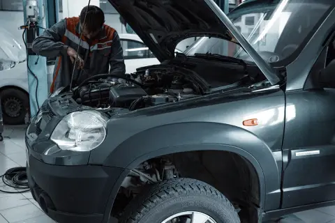Mechanik wymienia żarówkę w przednim reflektorze Skody Fabii 3.