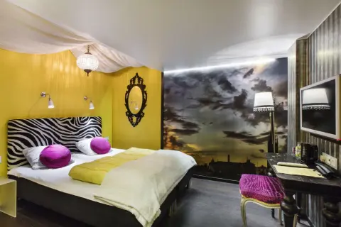 Ett mysigt eget rum på vandrarhem i Stockholm med zebra-mönstrat sänggavel, gul vägg och dramatisk molnhimmel som fondtapet.