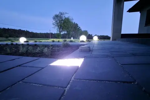 Nocny ogród rozświetlony kulistymi lampami, które tworzą magiczną atmosferę. W kostce brukowej wbudowane są dyskretne ledy, podkreślające ścieżkę.