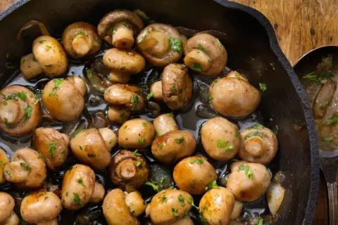 Champiñones salteados en sartén de hierro fundido, perfectos para tus recetas con champiñones. Un plato sencillo y delicioso.