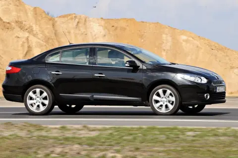 Czarny Renault Fluence jedzie po drodze, w tle piaszczyste wzgórza.