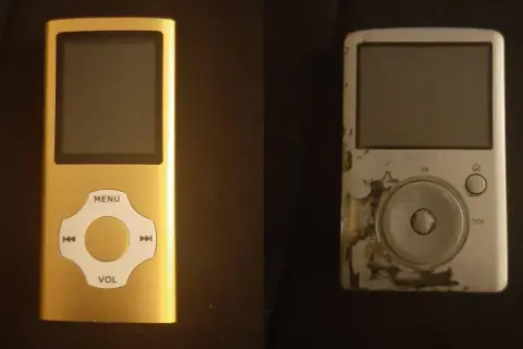 A new gold mp3 player sits next to a worn, scratched silver one.