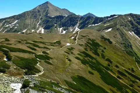 Wędrówka po skalistych graniach Tatr, gdzie ścieżki wiją się wśród kosodrzewin i resztek śniegu. To jedne z najtrudniejszych szlaków w Tatrach.