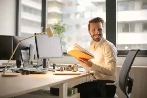 Ein Mann im Büro liest ein Buch. BWL: Was macht man da? Er lernt, wie man erfolgreich ist.