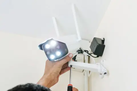 Montaż kamery Wi-Fi: ręka przykręca śrubę, przygotowując urządzenie do podłączenia.