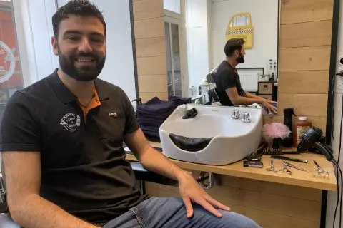 Le tonsor souriant, barbier dans son salon, entouré de ses outils de coiffure.