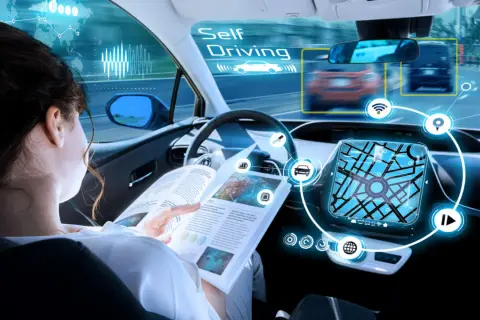 Donna legge un libro mentre l'auto guida da sola, mostrando la tecnologia di guida autonoma livello 4.