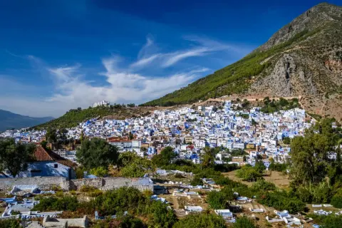 Vista panorámica de Chefchaouen, la ciudad azul, encaramada en una ladera montañosa. A pesar de su belleza, se rumorea que Chefchaouen es peligroso, con un cementerio en primer plano.