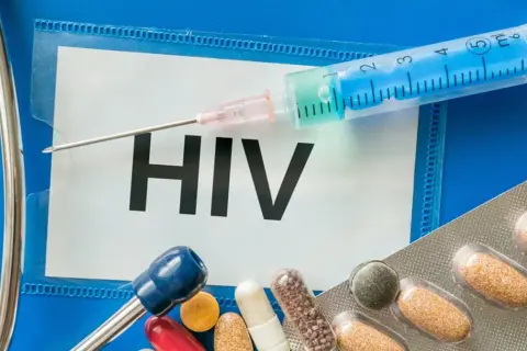 Strzykawka, tabletki i stetoskop na tle napisu HIV.