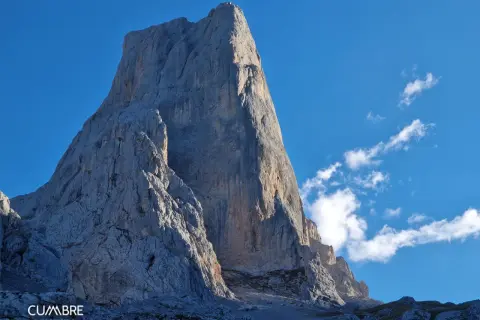 El imponente Urriellu se alza majestuoso bajo un cielo azul, invitando a contemplar el tiempo y la grandeza de la montaña.