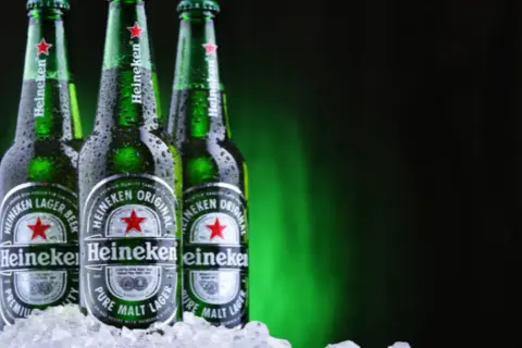 Trzy butelki Heineken, holenderskiej marki piwa, w lodzie.