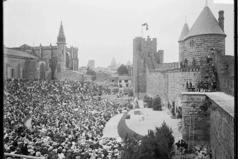 Vue d'un spectacle dans les arènes de Carcassonne, avec une foule nombreuse assise et la cité médiévale en arrière-plan.