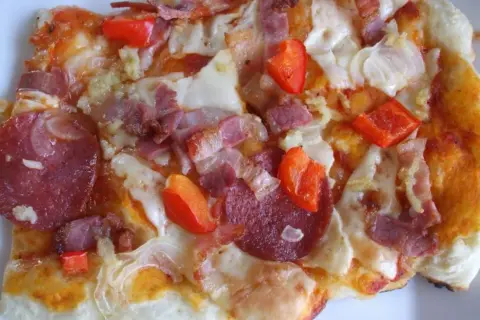 Pikantna pizza diavola z salami, boczkiem i papryką, gorąca i apetyczna.