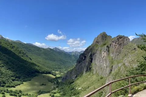 Un valle verde y montañoso con un arco natural en la roca, ideal para rutas circulares en Somiedo.