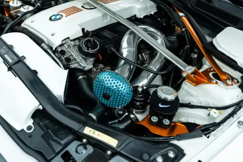 Motor tuning en un BMW: filtro de aire azul, intercooler cromado y refuerzo naranja.