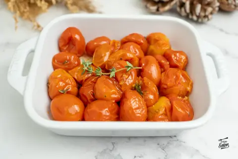 Tomates confitados en una fuente blanca, con ramitas de tomillo fresco. Un plato delicioso y aromático.
