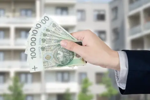 Dłoń trzyma banknoty 100 zł. Zastanawiasz się, ile wynosi dodatek mieszkaniowy?
