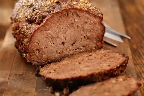 Un delizioso polpettone al forno, tagliato a fette su un tagliere di legno, pronto per essere gustato.