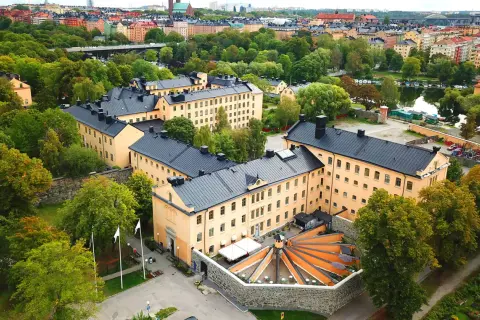 Långholmen vandrarhem, en före detta fängelsebyggnad i Stockholm, omgiven av grönskande träd och med en vacker utsikt över vattnet.