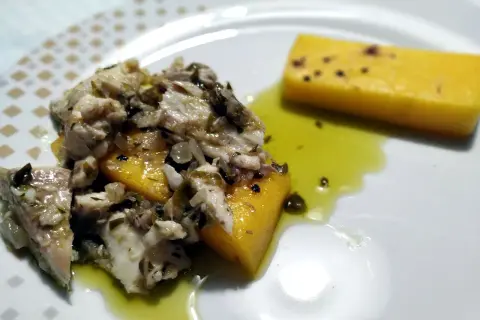 Piatto di luccio in umido con polenta gialla, condito con erbe aromatiche e olio. Un sapore autentico da provare!
