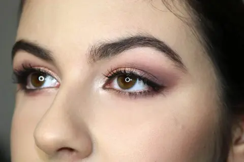 Occhi marroni con ombretto rosa e marrone, ciglia lunghe e eyeliner. Un esempio di come truccare gli occhi per un look sofisticato.