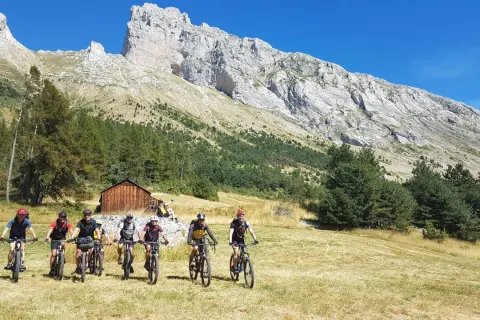 Groupe de cyclistes explorant le col de Gleize, avec une imposante montagne en arrière-plan.