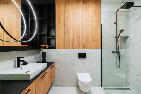 Nowoczesna łazienka inspiracje: drewniane panele, kamień terrazzo, czarna armatura i designerskie oświetlenie tworzą stylową przestrzeń.