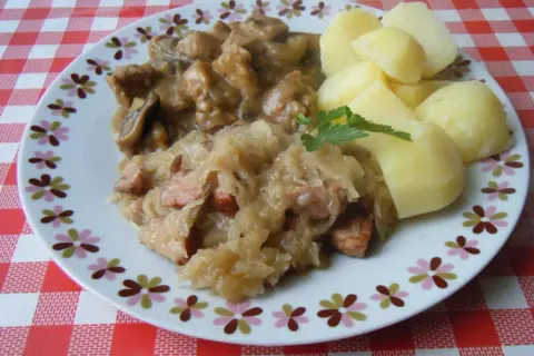 Pyszna kapusta kiszona gotowana z kawałkami mięsa i kiełbasy, podana z ziemniakami.