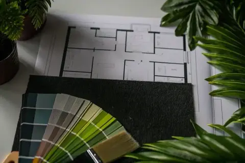 Floor plan, paint swatches, and a brush lay on a surface, ready for your next remodel.