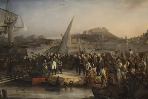 Napoleon anländer till Elba. En stor folksamling möter honom vid hamnen, med fartyg och en stad i bakgrunden.