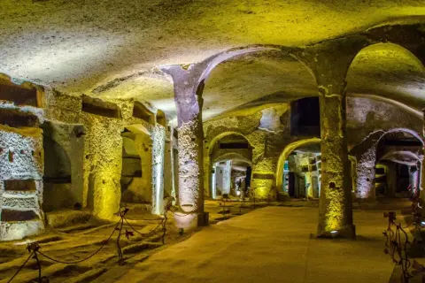 Un viaggio nelle catacombe di San Gennaro, un luogo suggestivo con tombe scavate nella roccia e colonne antiche.