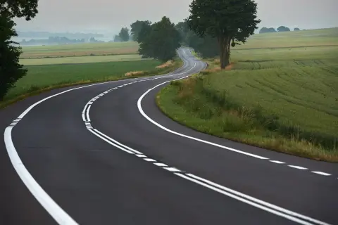 Droga wijąca się przez pola. Podwójna ciągła linia wyznacza pasy ruchu, przypominając, kiedy można przekroczyć podwójną ciągłą.