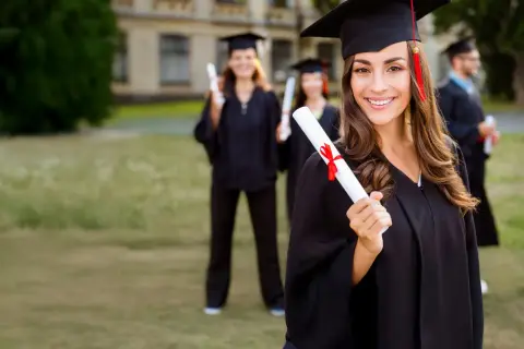 Absolventin mit Urkunde, bereit für MBA mit Fachwirt. Mehrere Studenten in Roben im Hintergrund.