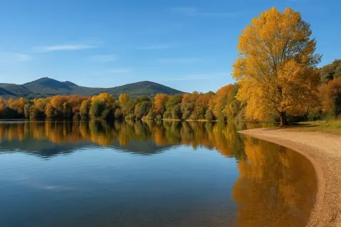 Un árbol dorado ilumina la orilla del lago de Carucedo, reflejándose en sus aguas tranquilas. Un lugar perfecto para un merendero.