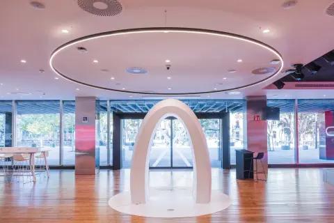 Un arco blanco futurista en el centro del espacio Xplora Ibercaja, con una iluminación circular en el techo y grandes ventanales al exterior.