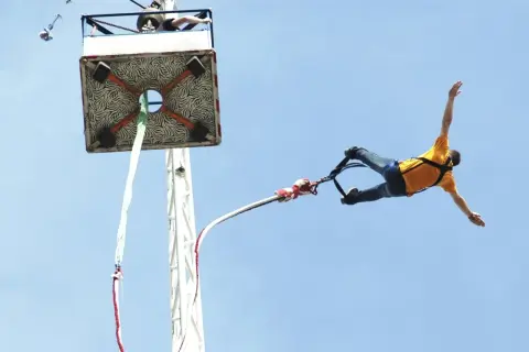 Człowiek w żółtej koszulce skacze na bungee. Zastanawiasz się, ile kosztuje skok na bungee? To niezapomniane przeżycie!