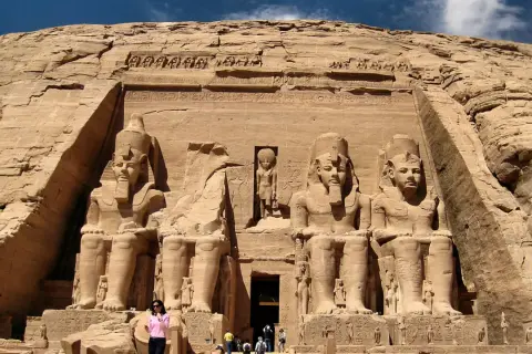 Gigantescas estatuas de Ramsés II flanquean la entrada del templo de Abu Simbel, Egipto. Un pequeño grupo de turistas admira la magnificencia de esta maravilla antigua.