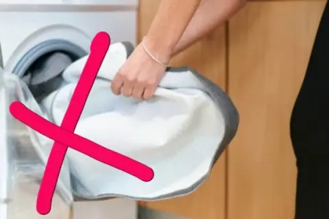 Rote Kreuze über einem weißen Wäschestück, das aus einer Waschmaschine genommen wird. Das zeigt, was darf nicht in den trockner.