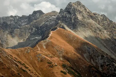 Jesienne, **czerwone wierchy szczyty** Tatr, z kamienistymi zboczami i ścieżką wijącą się po grani.