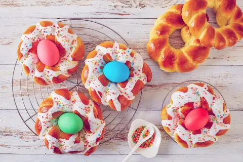 Bunte Osternester backen: Hefezöpfe mit Zuckerguss, Streuseln und gefärbten Eiern.