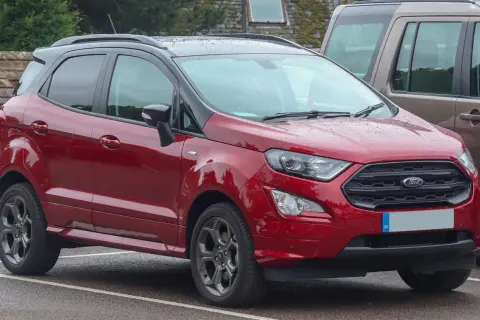 Czerwony Ford EcoSport 2018 z czarnym dachem, zaparkowany na mokrym parkingu.
